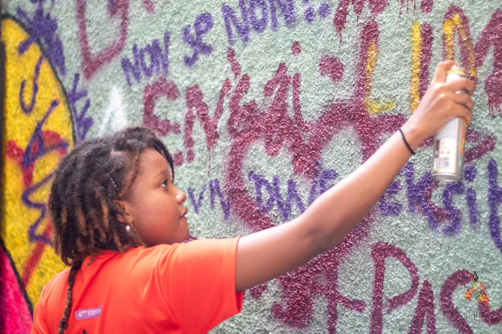 A girl spray-painting a wall covered in slogans